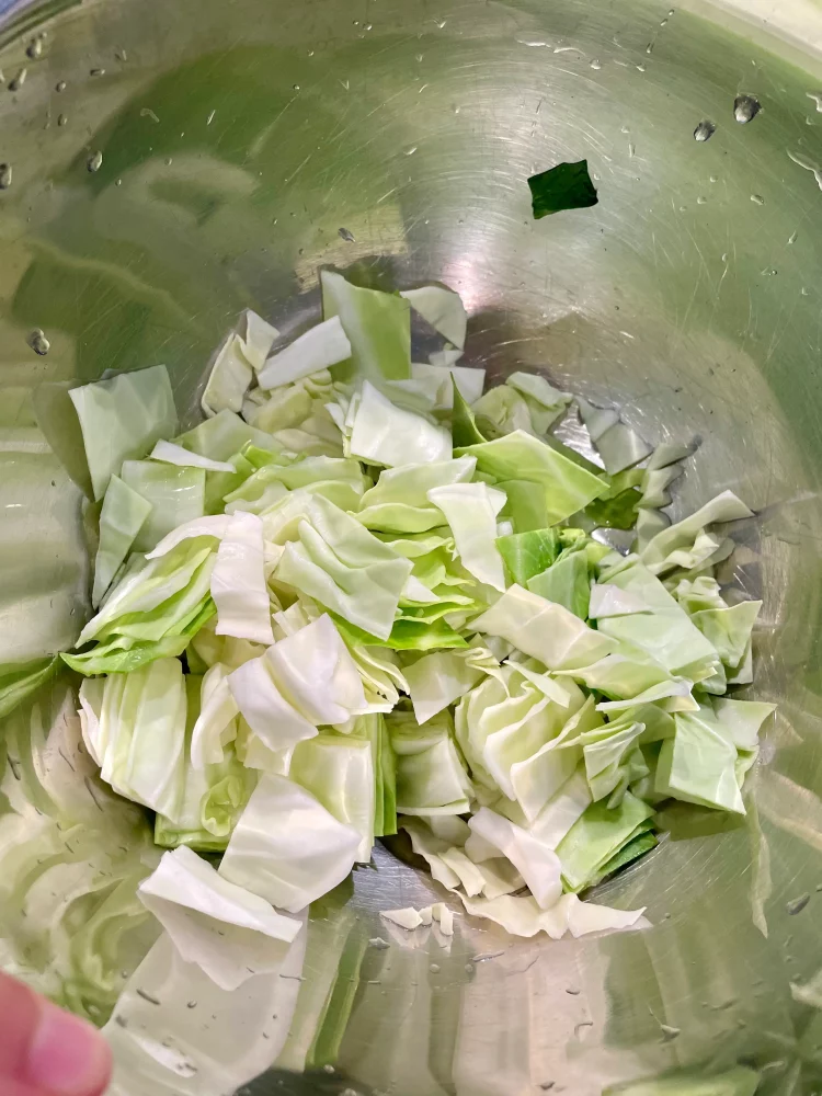 Sweetheart cabbage cut into bite-sized pieces and washed, drying on the side.