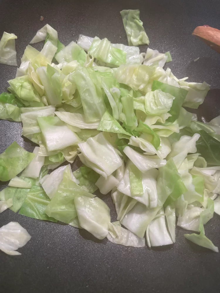 Sweetheart cabbage being stir-fried in a pan with cooking oil on medium-high heat.