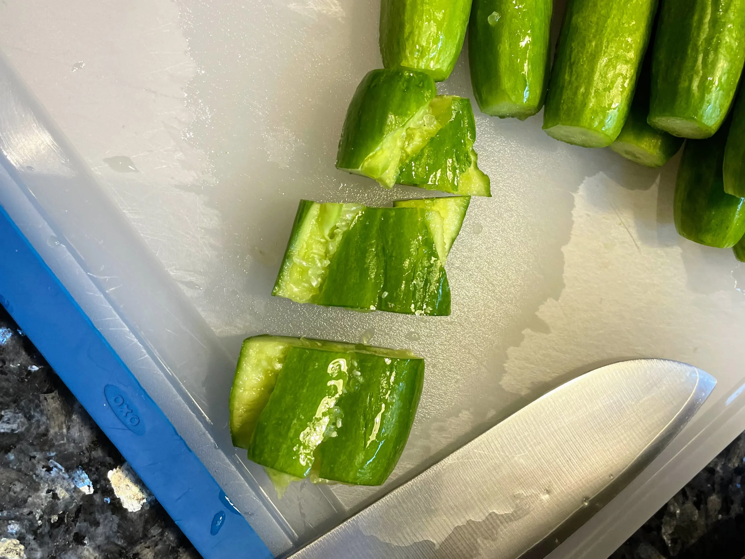 Pressed baby cucumbers cut into bite-sized pieces, arranged on a cutting board.