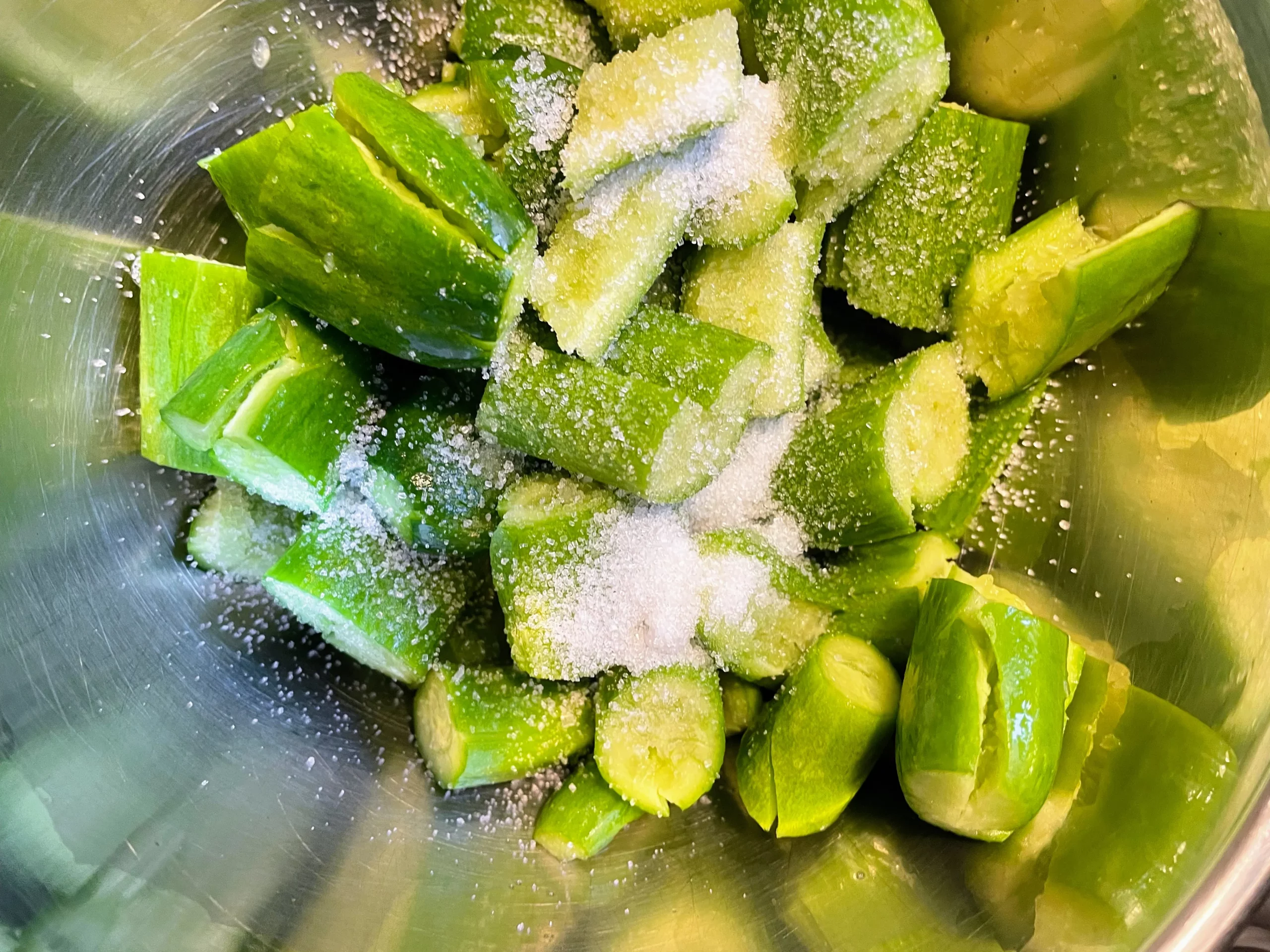 Baby cucumbers marinating in salt and sugar, a step to make them crunchy and reduce water content.