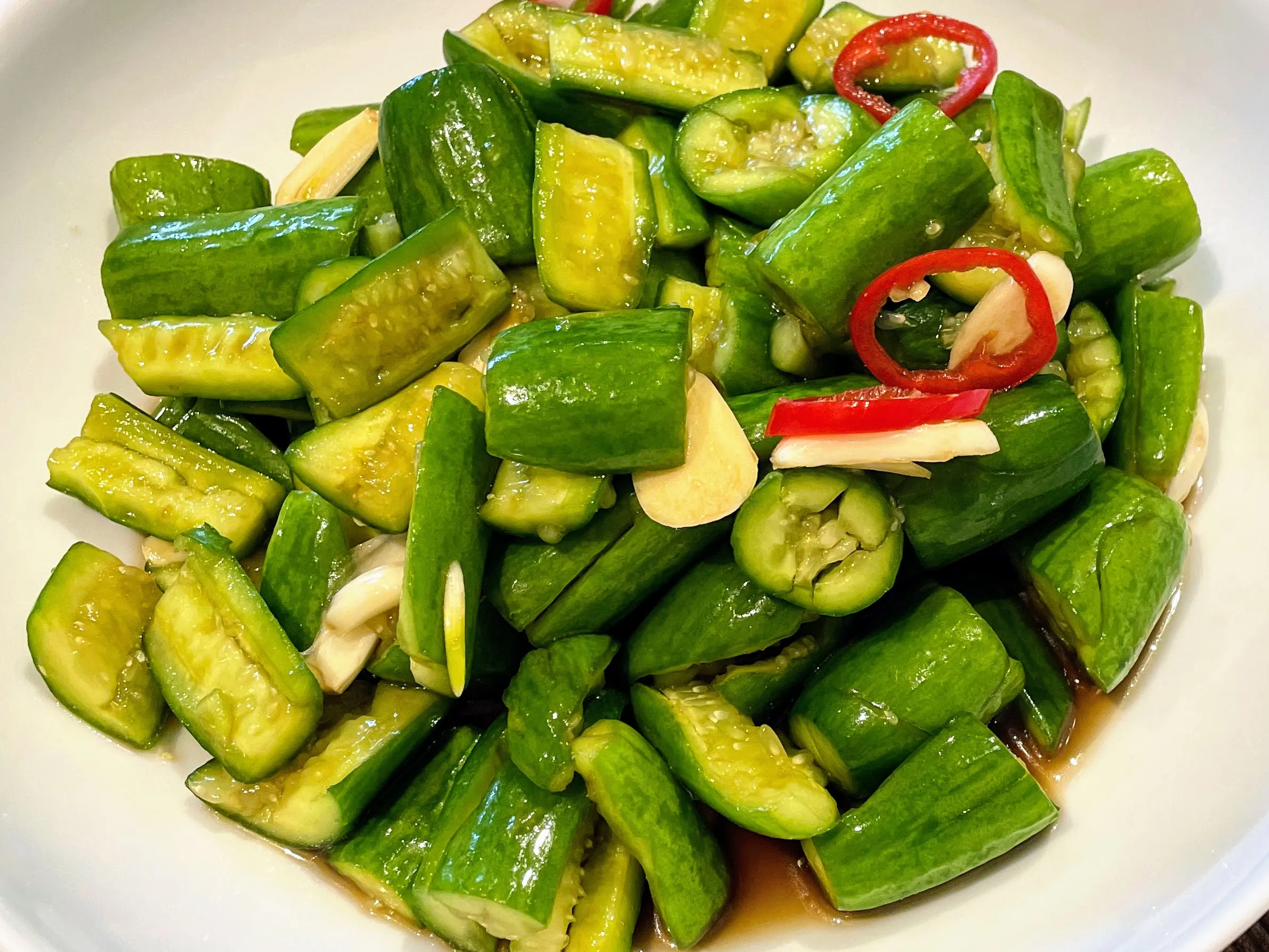 A plated Chinese cucumber salad garnished with chili and garlic, ready to serve as a refreshing side dish.