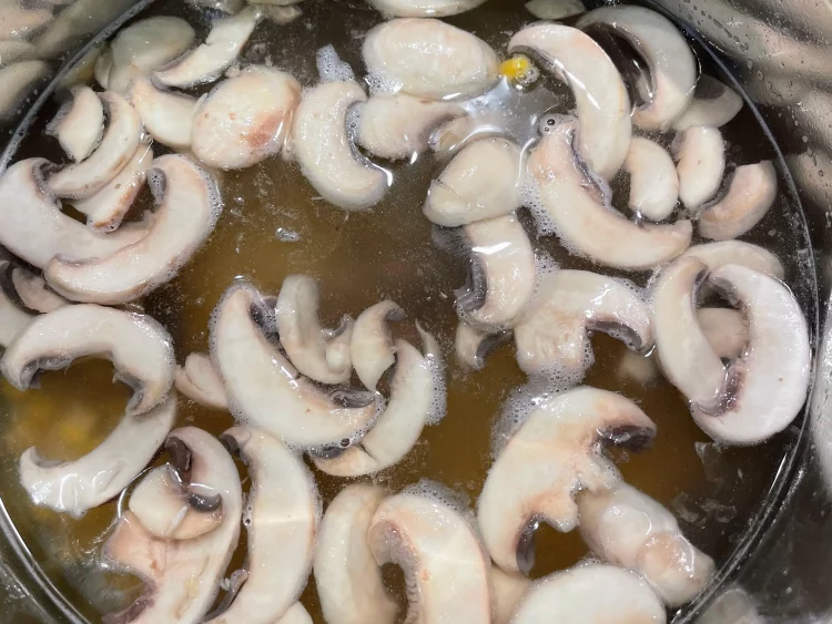 Sweet corn added to a pot along with mushroom water and 6-7 cups of water, ready to simmer into a creamy congee.