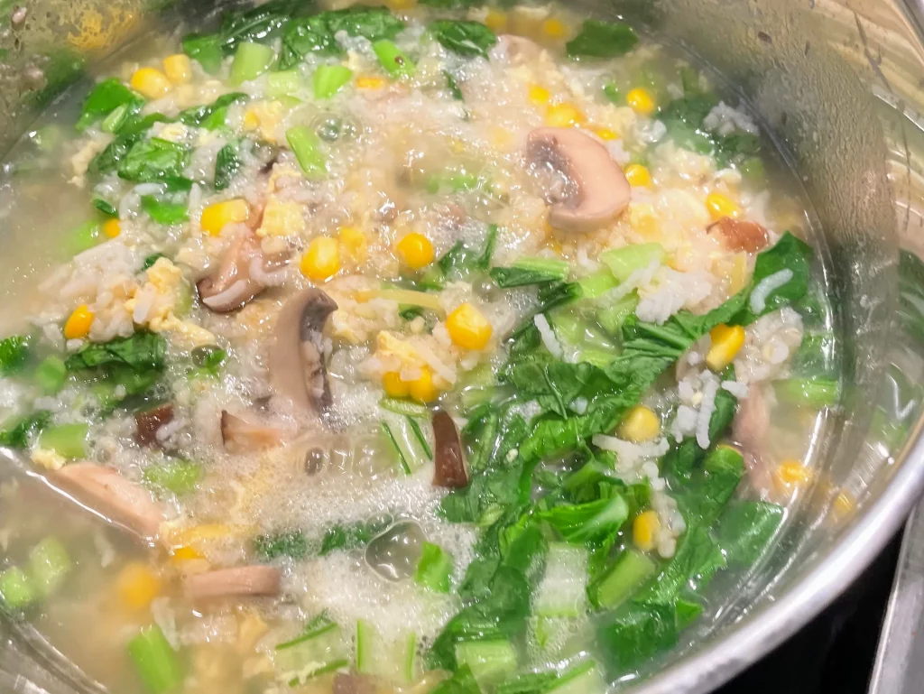 Chopped leafy greens, such as Choi Sum, stirred into the congee as it cooks for another 5-10 minutes.