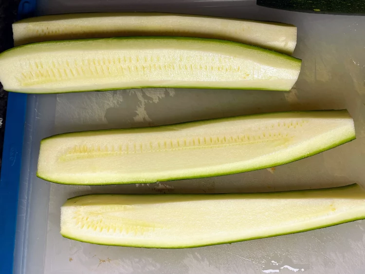 Courgette sliced into quarters with seeds removed for stir fry preparation.