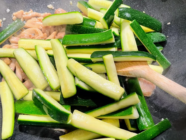 Courgette added to the wok, cooking with the chicken for a flavorful stir fry.