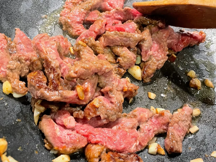 Stir-frying marinated beef in a hot wok with Shacha sauce